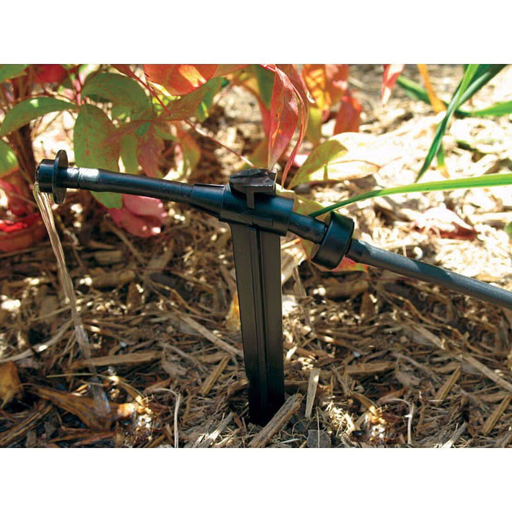 XERI Bug Emitter PC Drip irrigation system in a garden setting with plants and soil.